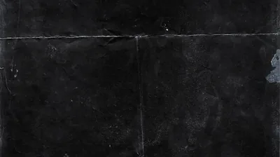 A creased black surface crossed by faint fold lines, a pale smudge near the right edge breaking the flat tone.