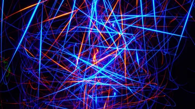 Dozens of blue and orange laser streaks cross at random over black, dense enough that a notch or status bar disappears into the tangle.