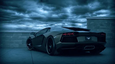 Rear three-quarter on a bare rooftop deck, heavy blue-grey cloud stacked behind the car and its hexagonal tail lights burning red against the gloom.