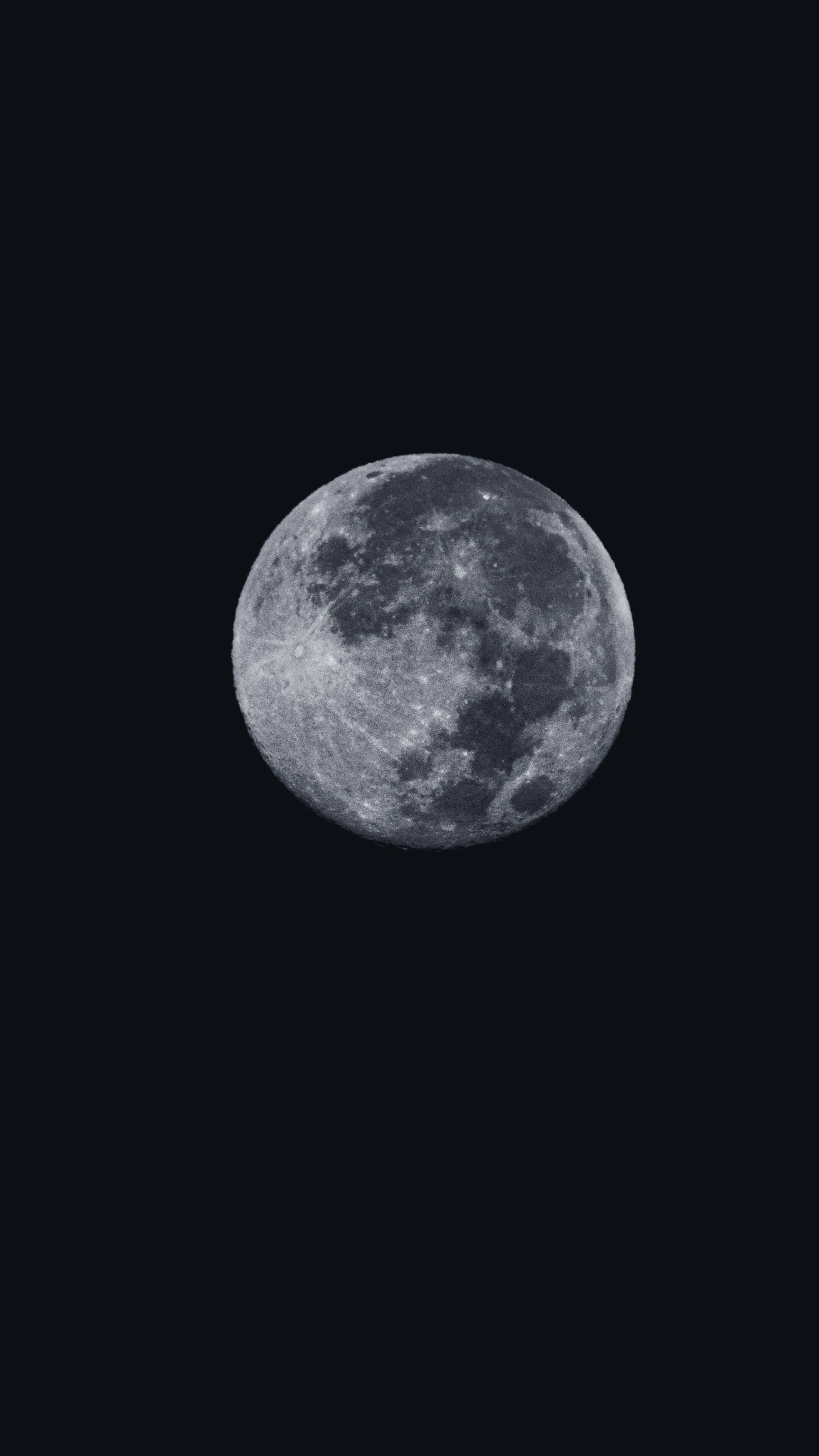 The moon hangs above centre in an otherwise empty black frame, its craters and dark maria clearly visible along the lower half of the disc.