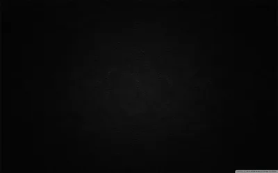 Deep black leather with the faintest circular sheen at the centre, the grain only readable where that light reaches.