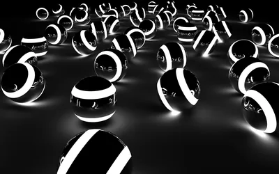 Glossy black spheres ringed by bright white bands rest on a reflective floor, the light falling off into darkness at the back.