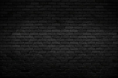 A wide expanse of black brick brightens slightly through the middle and falls to solid darkness at the four corners, the joints still visible.