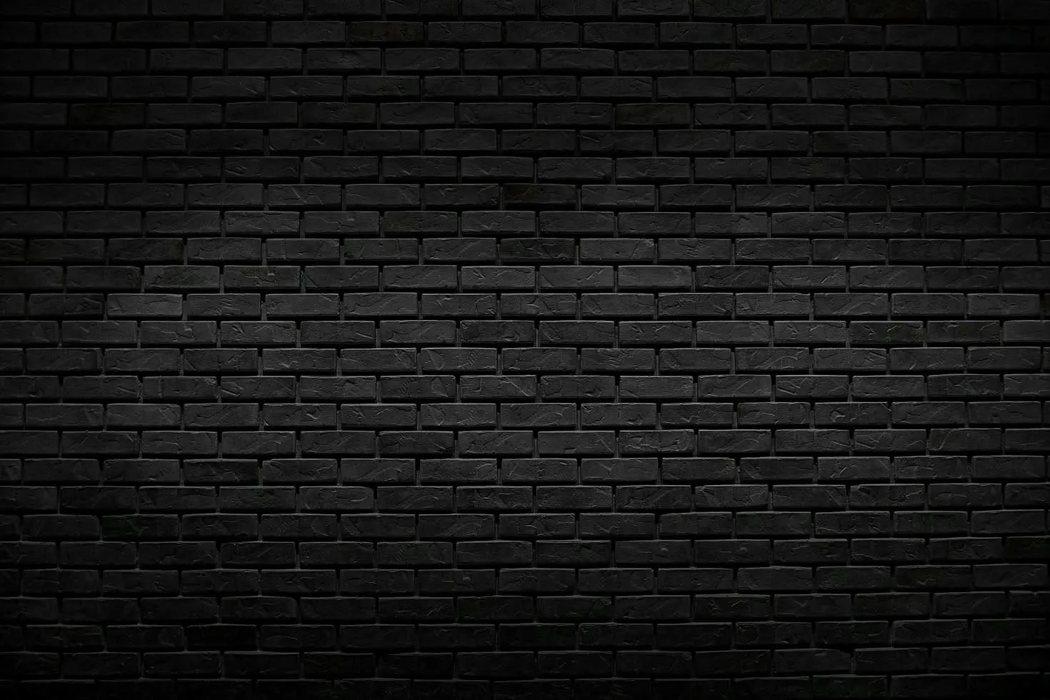 A wide expanse of black brick brightens slightly through the middle and falls to solid darkness at the four corners, the joints still visible.
