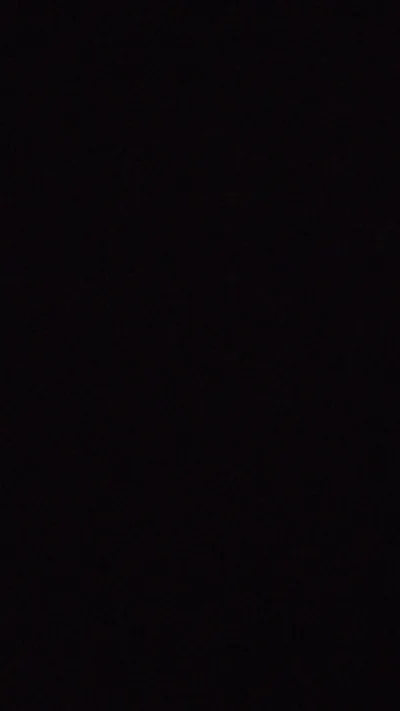 A tall frame of almost solid black, only a whisper of texture and a slightly warmer patch near the bottom breaking the flat field.