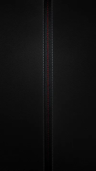 Fine-grain black leather split down the middle by a stitched seam, red thread just catching the light.