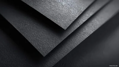 Three sheets of textured black card fanned across each other, the top edges catching a soft light while the background falls away.