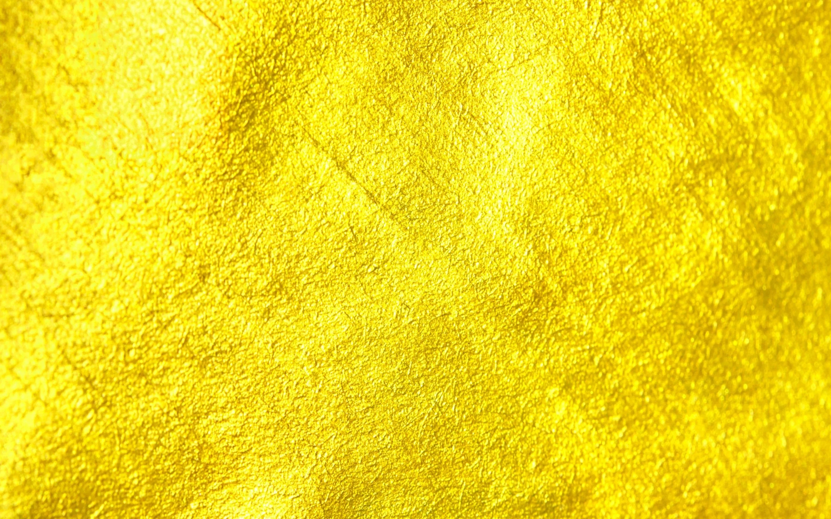 A scraped, plaster-like metallic surface in lemon gold, faint diagonal strokes and pitting spread evenly across the whole frame.