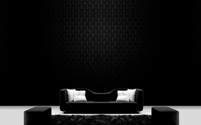 A low black sofa with white cushions sits centred against a dark patterned wall, two blocks flanking it on a bare white floor.