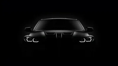 Almost the whole frame is black; only a thin rim of light traces the roof and bonnet of a BMW while its four headlight rings burn white.