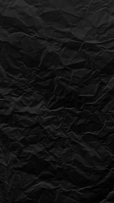 Sheet of black paper that has been screwed up and flattened again, side lighting picking out every crease and leaving the folds in shadow.