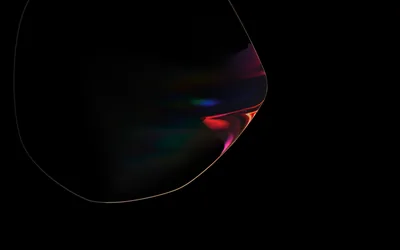 A large dark bubble curves in from the left with rainbow light bending along its rim, red and green catching where the surface thins.