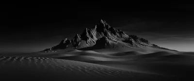A jagged peak rises from smooth dark dunes under a black sky, lit just enough to show its ridgeline.