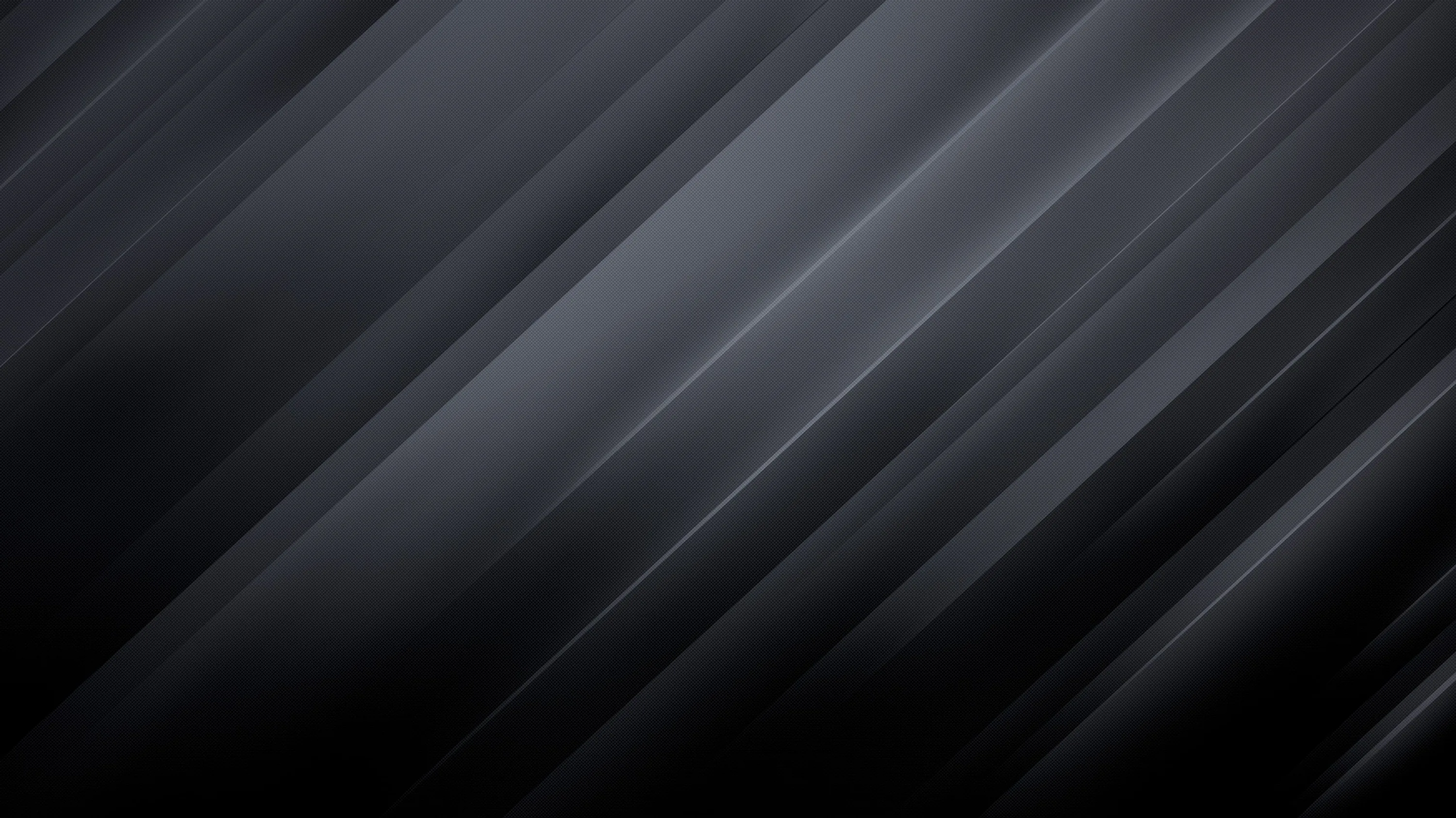 Long brushed streaks run diagonally across a dark metal surface, catching light in irregular bands.