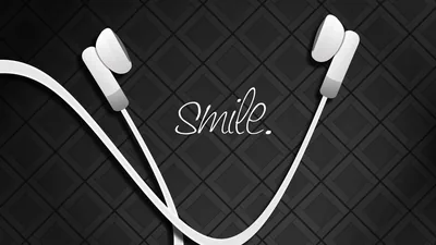 White earphones curl across a quilted dark surface with a single handwritten word between them.