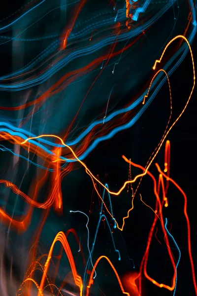 Long-exposure light trails in orange, blue and yellow whip across the dark — an abstract that hides a notch and status bar equally well.