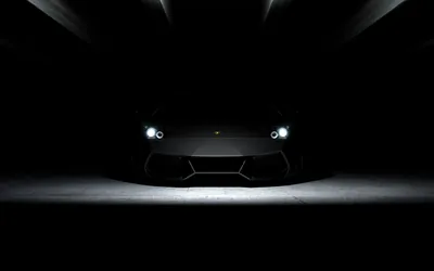 Only two lit headlights and a small pool of floor light mark out a wedge-shaped supercar, the rest of the frame falling to near-total black for OLED.