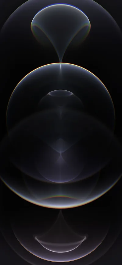 Three translucent graphite spheres stack down the frame, the largest sitting in the middle, a faint rainbow flare where their rims cross.