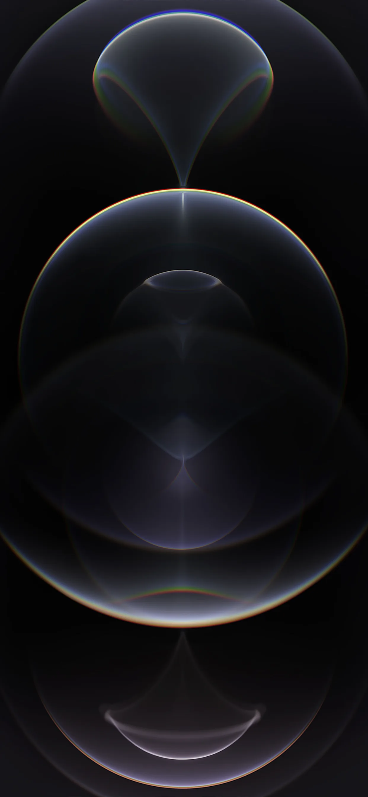Three translucent graphite spheres stack down the frame, the largest sitting in the middle, a faint rainbow flare where their rims cross.