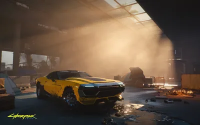 Sunbeams cut through haze from the right onto a parked yellow muscle car in a wrecked garage, the left half falling into brown shadow.