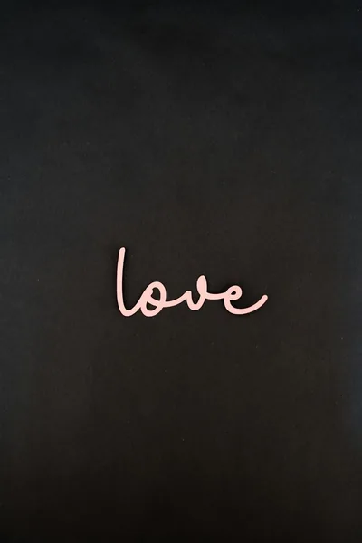 The word love written in loose pink script sits low on a chalky black wall, the whole upper half of the frame left empty for icons.