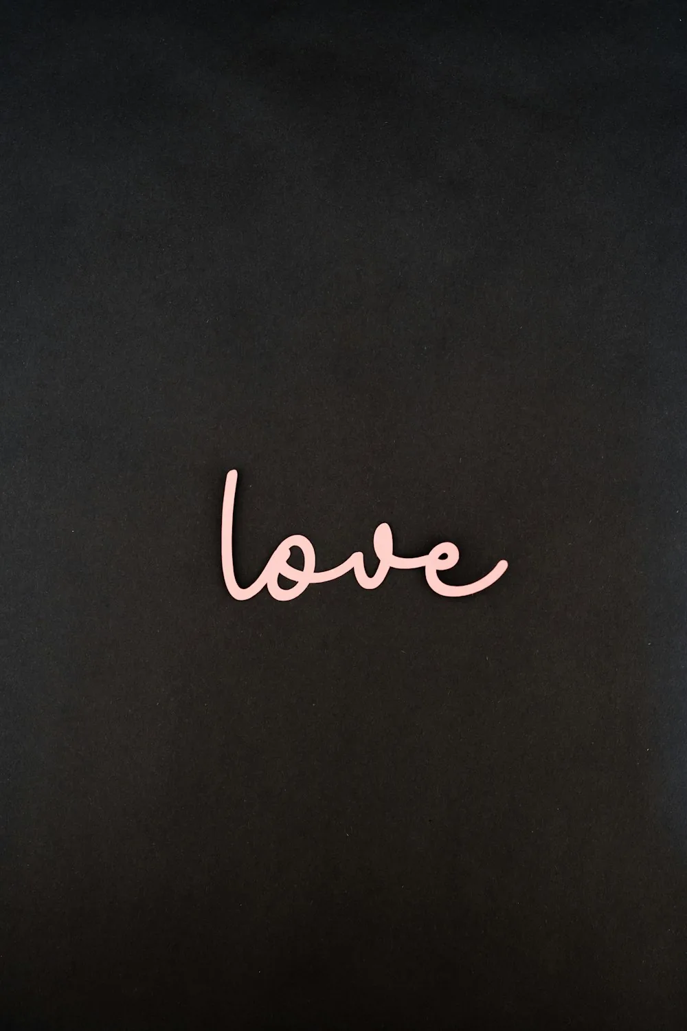The word love written in loose pink script sits low on a chalky black wall, the whole upper half of the frame left empty for icons.