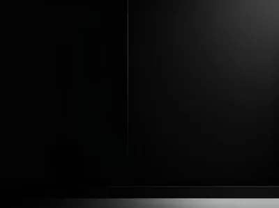 A CGI studio corner in near-black, one thin bright seam splitting the back wall and a low platform catching a faint edge of light along its front.