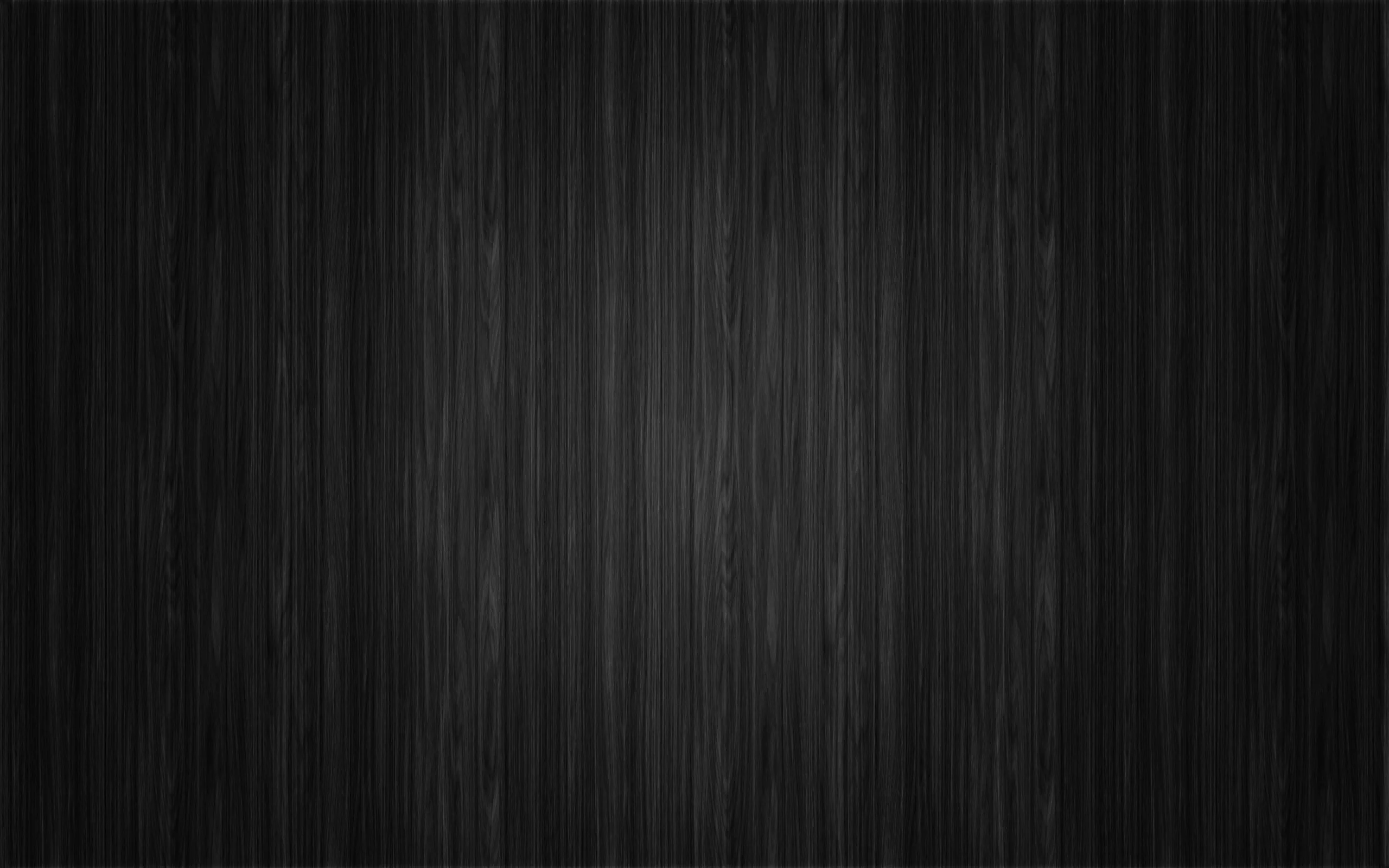 Fine vertical grain lines run the full height of a near-black timber surface, brightest at the top edge.