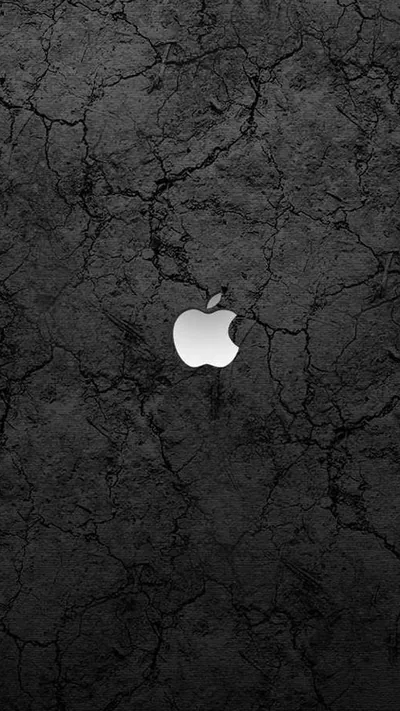 A white Apple mark glows at the centre of a heavily cracked grey-black stone surface, the fissures running out toward every corner.