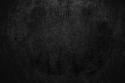 A close-up of creased black leather, faint scratches running through the middle while a heavy vignette darkens all four corners.