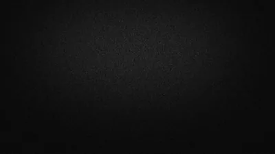 A near-solid black surface covered in fine grain, with the faintest lift of grey through the centre and the edges falling into full shadow.