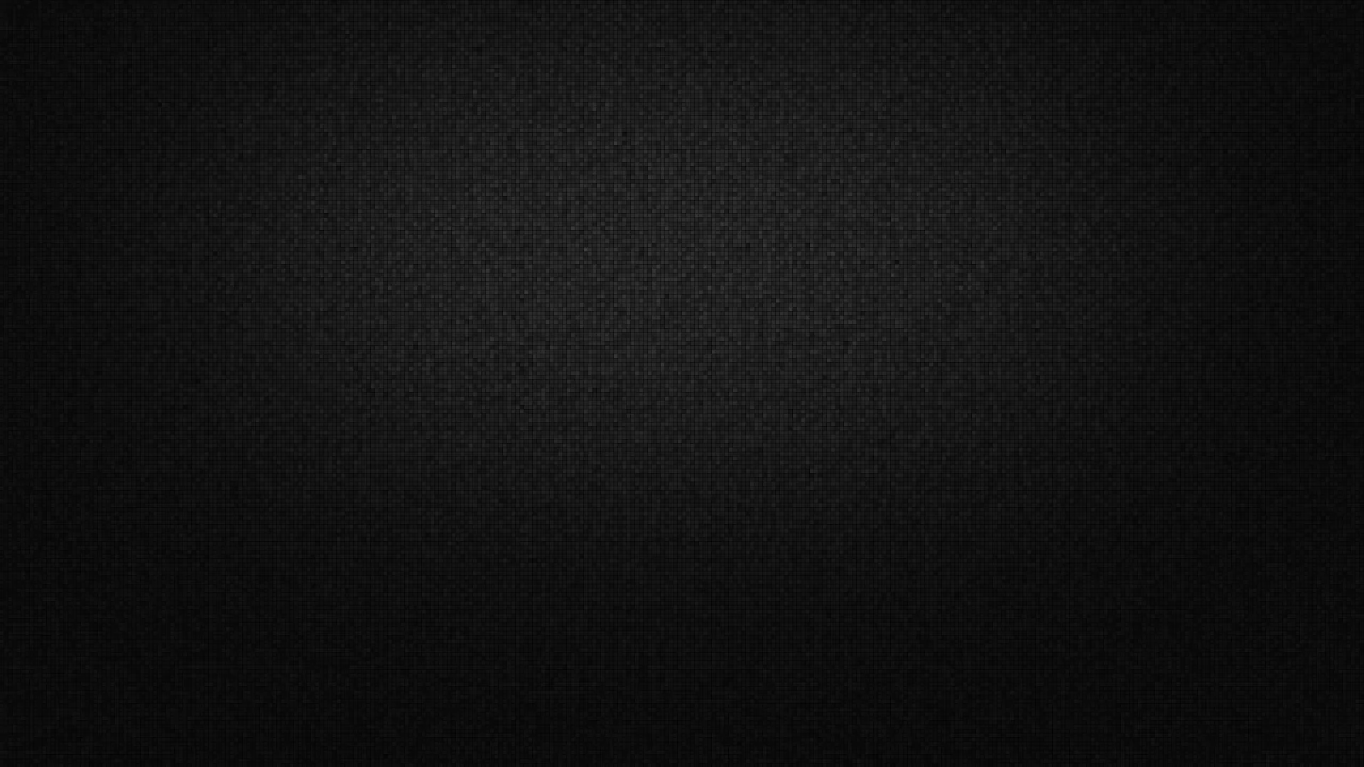 A near-solid black surface covered in fine grain, with the faintest lift of grey through the centre and the edges falling into full shadow.