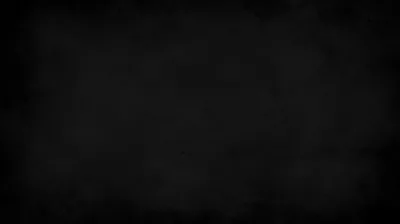 A dark matte surface with faint chalk-dust smudges through the middle, dimming to solid black at the corners.