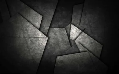 Angular concrete panels overlap across the frame, edges catching a thin highlight while the surrounding gaps sink into black.