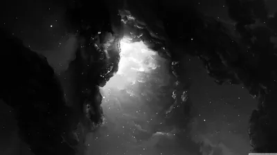 A glowing cloud of gas opens up between two banks of dark dust, stars scattered thinly through the gap.
