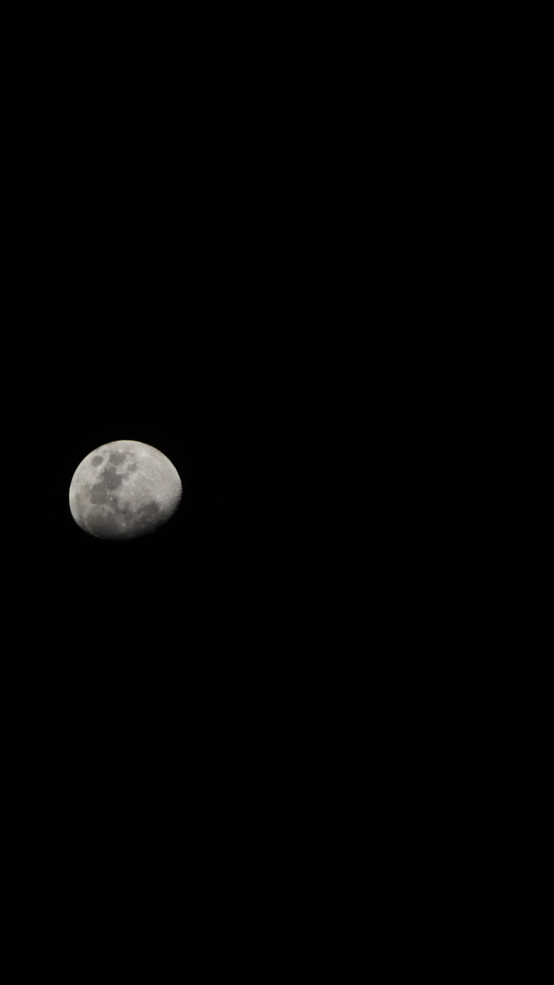A waning moon sits high on the left with craters clearly visible, the rest of the sky left completely black.