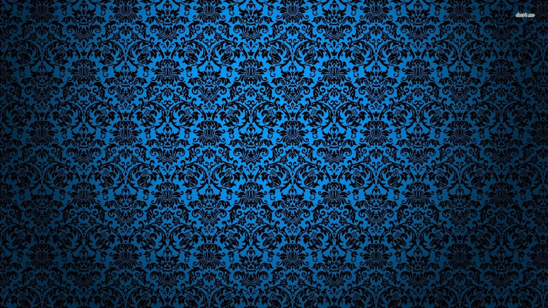 A repeating damask motif printed in bright blue over black, evenly tiled across the whole wall with the corners dropping into shadow.