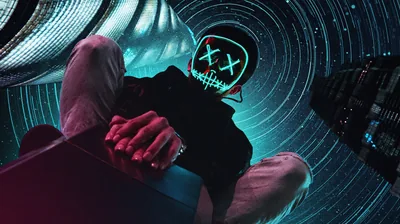 Shot from below, a man in a wire-light mask with X eyes looms against spiralling star trails, a dark tower edging in on the right.