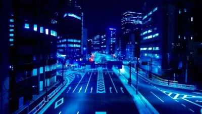 A night avenue curves between office towers, every window and road marking tinted the same electric blue, with the empty street glowing brightest at centre.