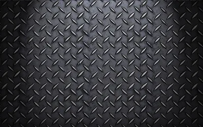 Raised diamond treads cover a dark steel plate, worn brighter through the centre and dimming to black at every corner.