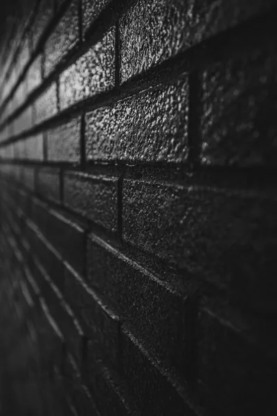 Glazed black bricks recede at a steep angle, the nearest courses crisp and grainy while the far end blurs into bokeh.