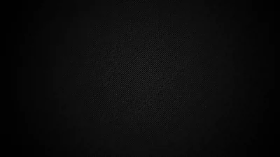 A close-up of tightly woven dark cloth, the thread grid only visible where light grazes the middle before the vignette pulls the corners into black.