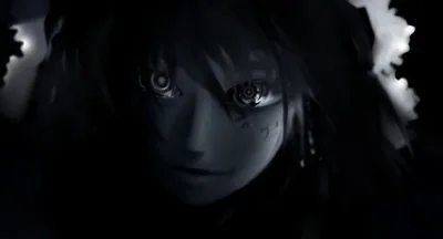 A face pushes out of near-total black, only the wide eyes and a thin blue edge along the hair catching any light.