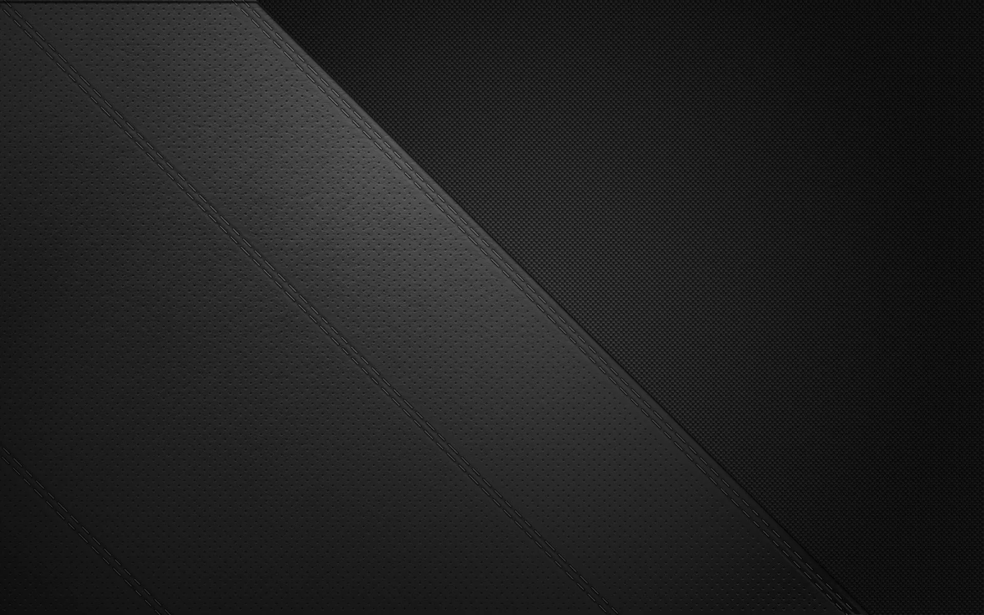 A clean diagonal divides two shades of near-black, both surfaces carrying a fine leather-like grain.