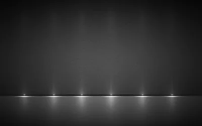 Six small downlights spaced along the base of a dark grey wall, each reflected in the glossy floor, while the upper two-thirds stays dim for desktop icons.