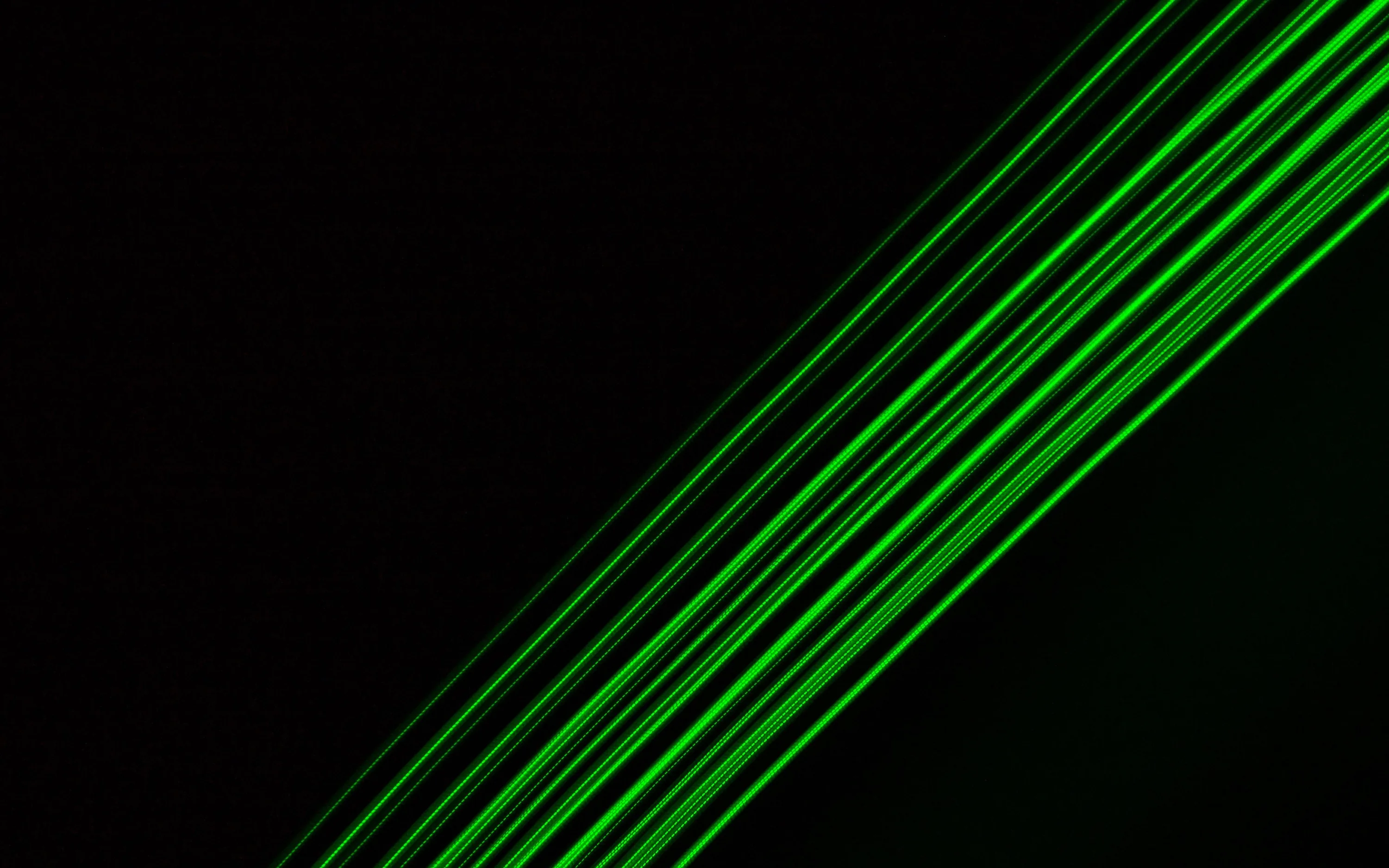 A bundle of thin green laser lines cuts diagonally from the lower left, leaving the upper corner in solid black.