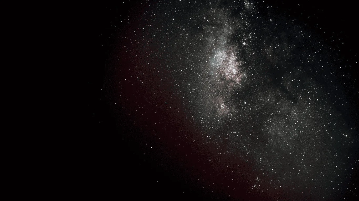 The Milky Way core burns in the upper right while the rest of the sky stays close to black, a faint red airglow bleeding in from the left.