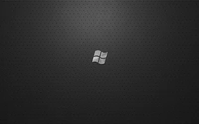 A small pale four-flag Windows logo sits at the centre of a charcoal cloth weave, the texture lightening slightly behind it.