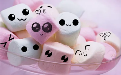 Pastel marshmallows with inked faces pile up in a glass bowl, shot close so the blurred pink upper corners are the calmest spots for text.