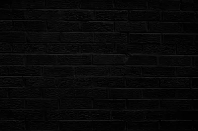 Flat black bricks run in even courses across the frame, the mortar joints just visible and the light falling off toward the bottom.